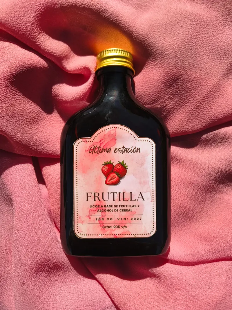 Botella de licor artesanal de frutilla de Última Estación sobre una tela rosa