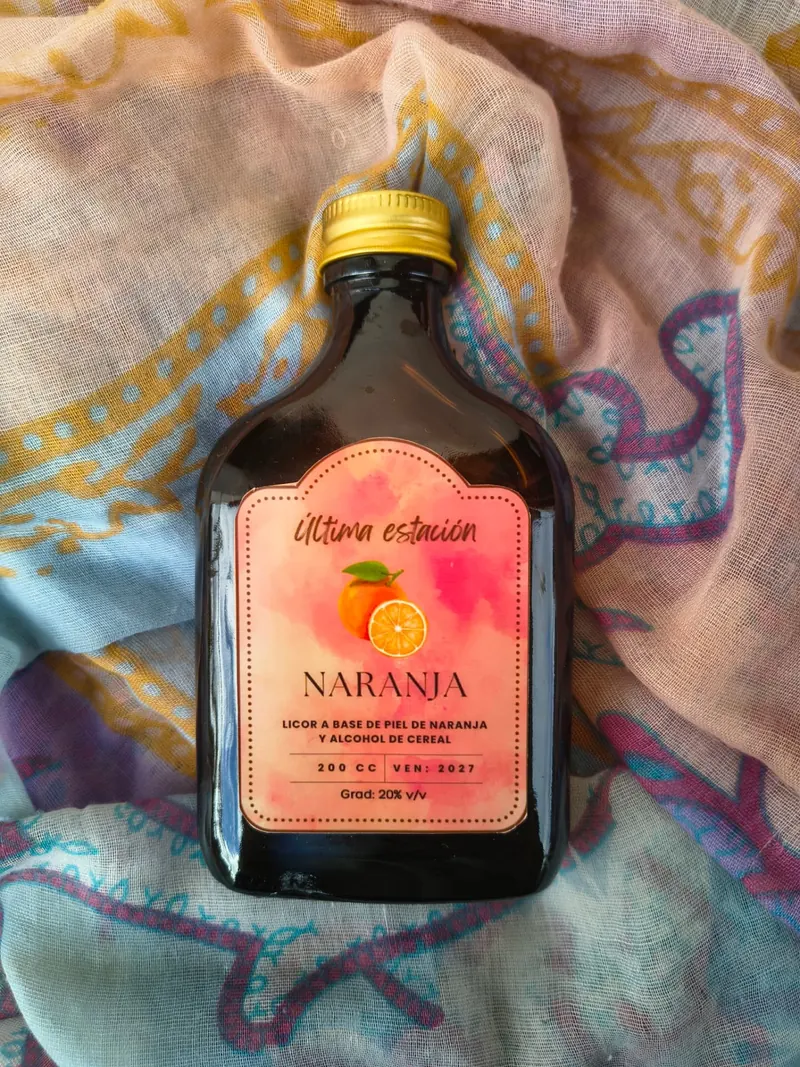 Botella de licor artesanal de naranja de Última Estación sobre un pañuelo estampado