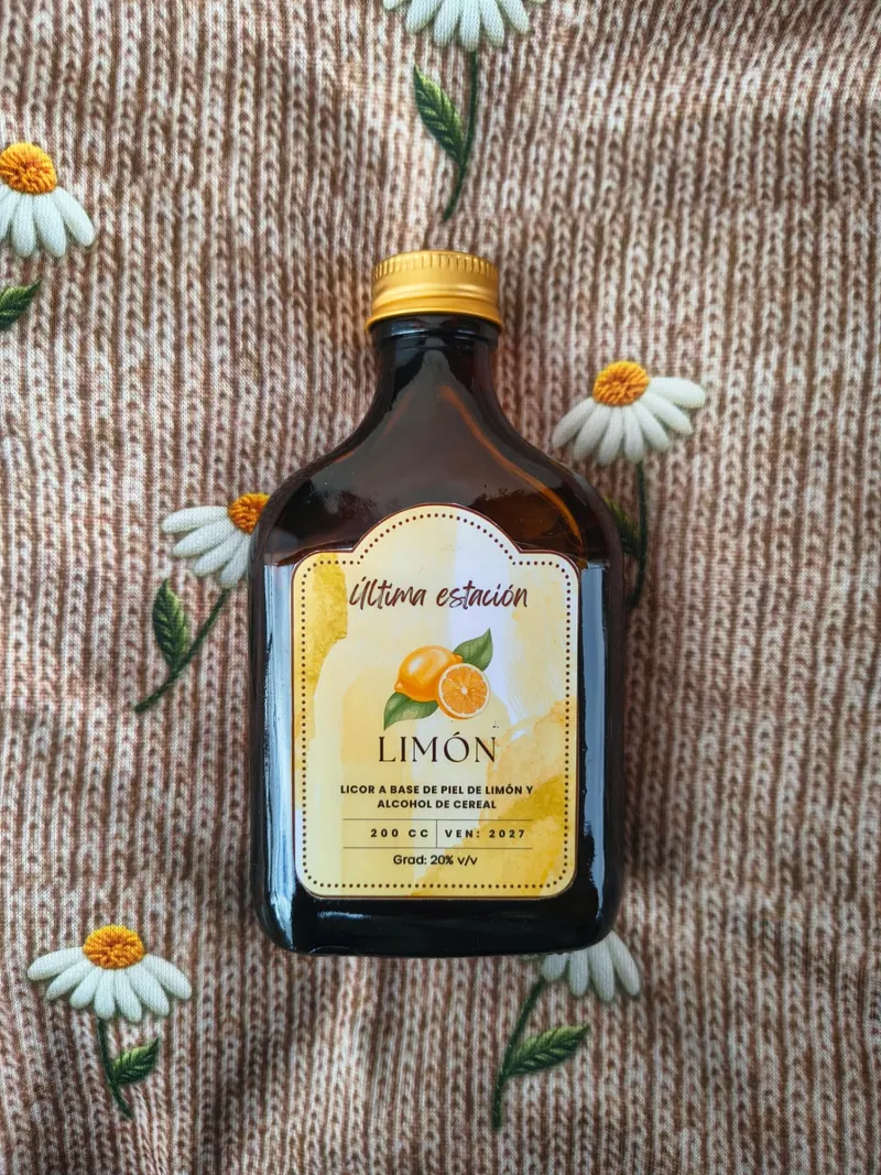 Botella de licor artesanal de limón de Última Estación sobre un tejido con margaritas bordadas