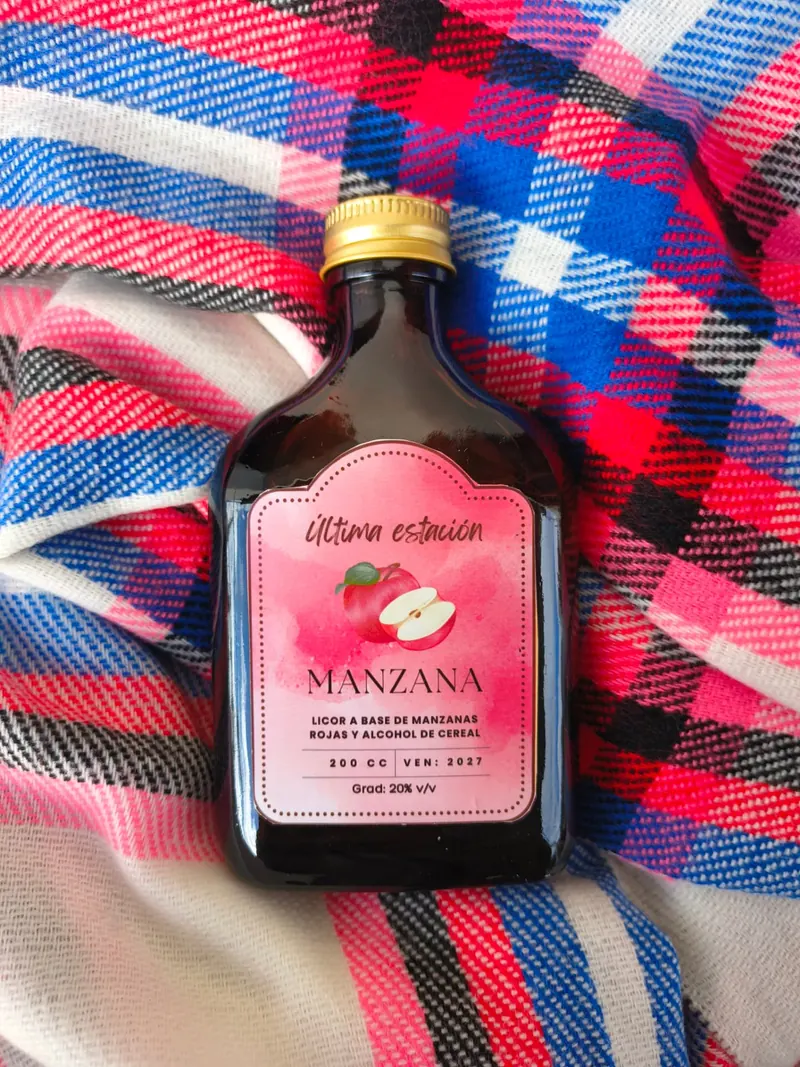 Botella de licor artesanal de manzana de Última Estación sobre una manta a cuadros