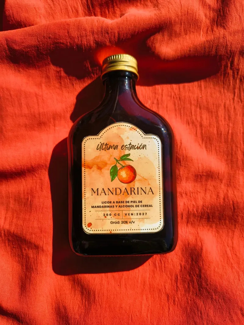 Botella de licor artesanal de mandarina de Última Estación sobre una tela roja